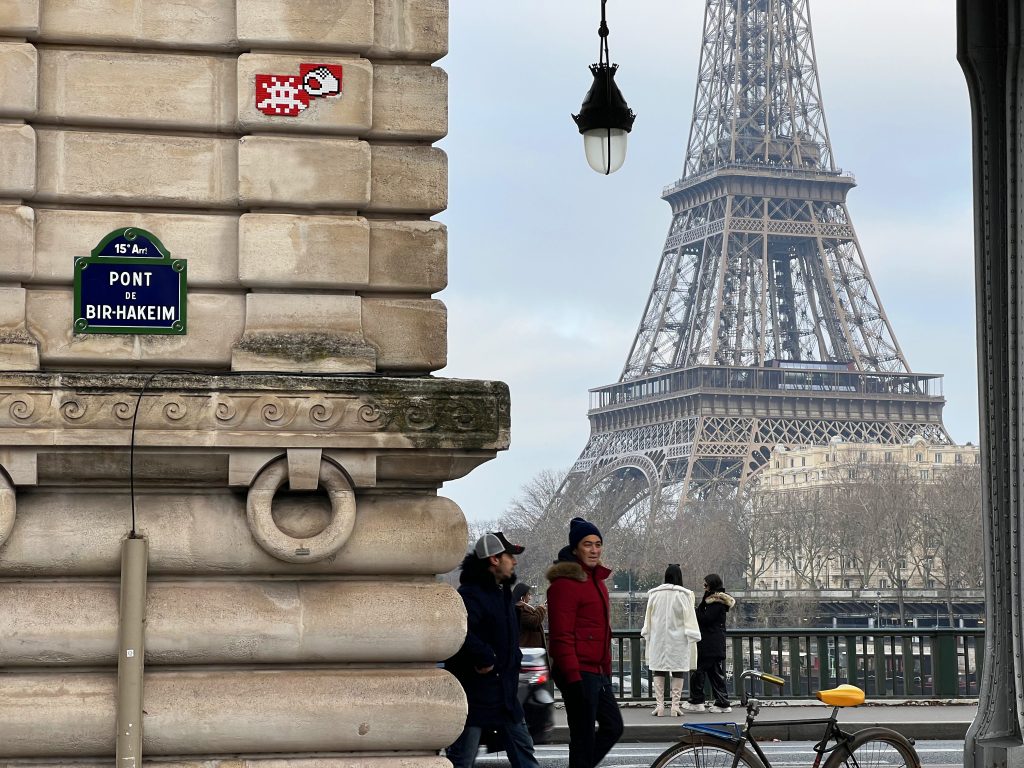 Invader mosaic on the Bir Hakeim Bridge in Paris, with the Eiffel Tower framed beautifully in the background.