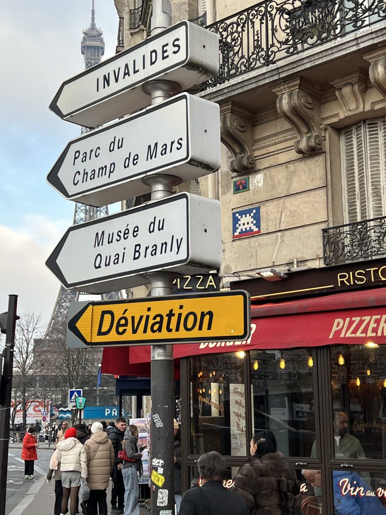 Invader mosaic artwork near the Eiffel Tower, blending iconic street art with the backdrop of Paris's most famous landmark.