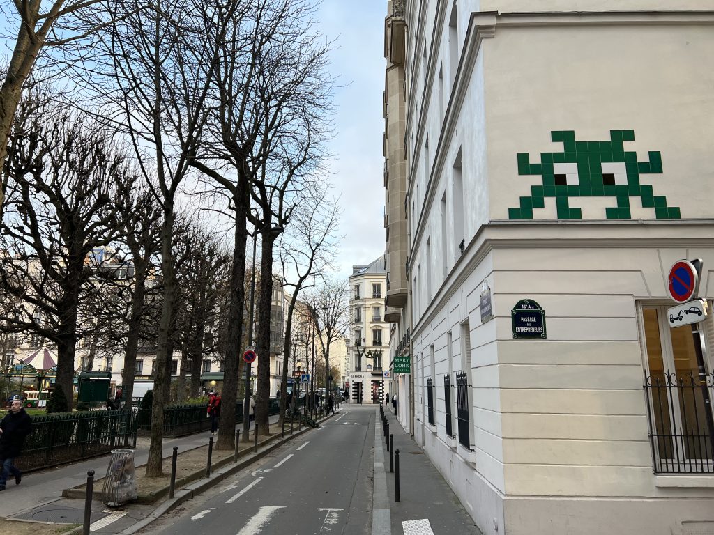 Street art by Invader at Place du Commerce, Paris, featuring a mosaic pixel artwork on a building facade, blending urban creativity with the charm of the Parisian neighborhood.